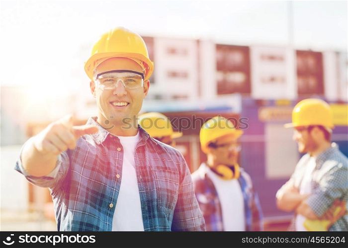 business, building, construction, gesture and people concept - group of smiling builders in hardhats pointing finger on you outdoors