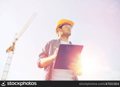 business, building, paperwork and people concept - builder in hardhat with clipboard outdoors