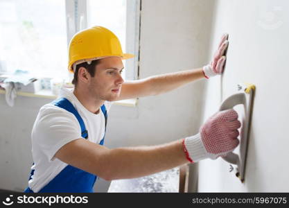 business, building, profession and people concept - builder with grinding tool indoors