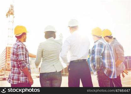 business, building, teamwork and people concept - group of builders and architects in hardhats with blueprint on construction site. group of builders and architects at building site