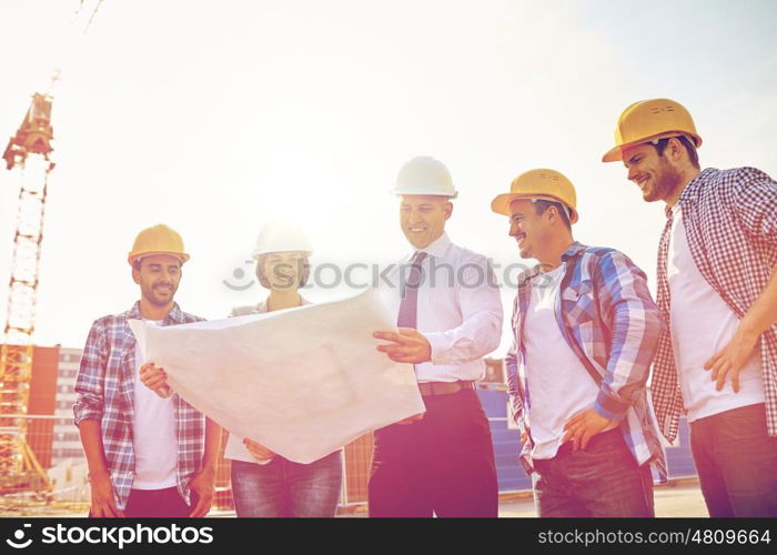 business, building, teamwork and people concept - group of builders and architects in hardhats with blueprint on construction site