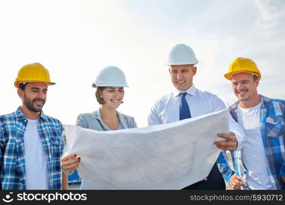 business, building, teamwork and people concept - group of builders and architects in hardhats with blueprint on construction site