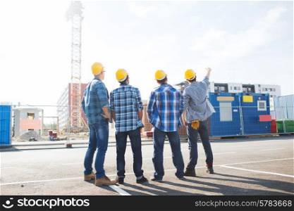 business, building, teamwork and people concept - group of builders in hardhats outdoors from back