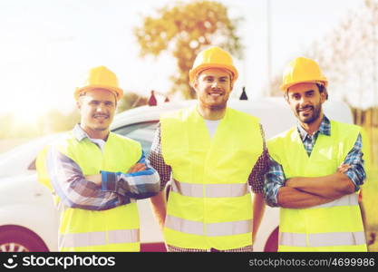 business, building, teamwork and people concept - group of smiling builders in hardhats on car background outdoors