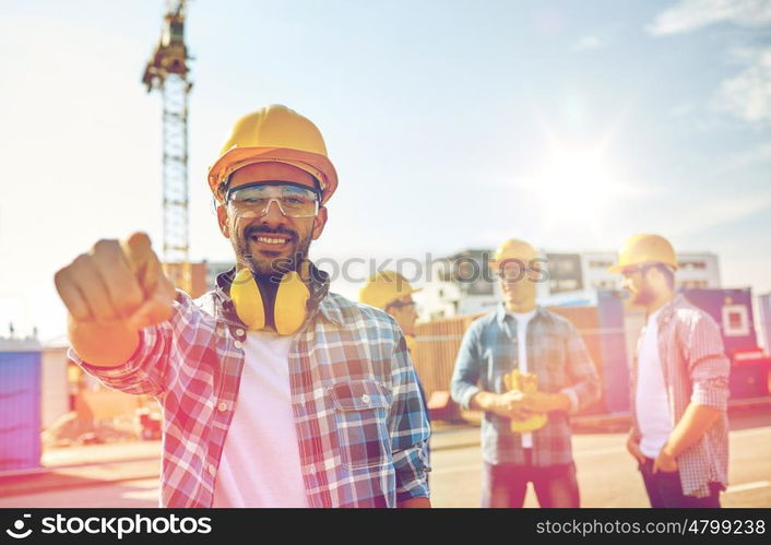 business, building, teamwork and people concept - group of smiling builders in hardhats pointing finger at you on construction site