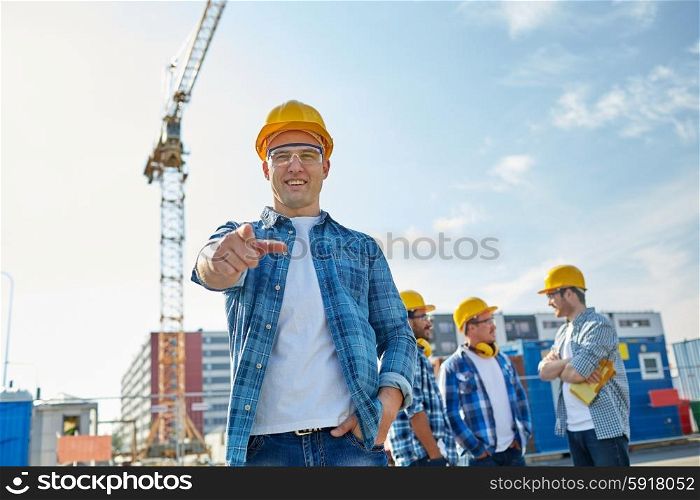 business, building, teamwork and people concept - group of smiling builders in hardhats pointing finger at you on construction site