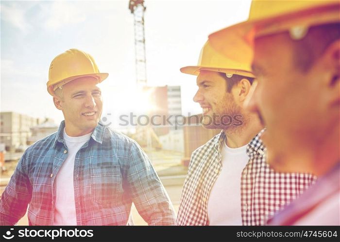 business, building, teamwork and people concept - group of smiling builders in hardhats at construction site