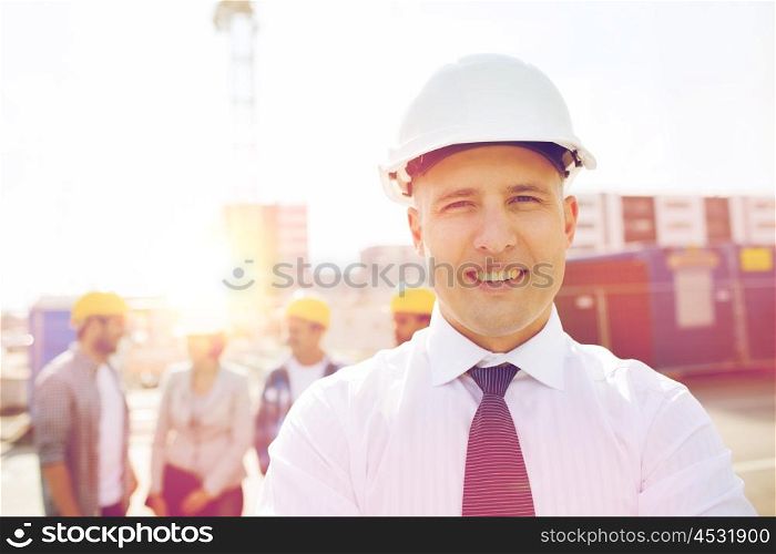 business, building, teamwork and people concept - group of smiling builders in hardhats outdoors. group of smiling builders in hardhats outdoors