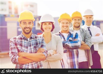 business, building, teamwork and people concept - group of smiling builders in hardhats outdoors. group of smiling builders in hardhats outdoors