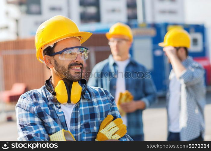 business, building, teamwork and people concept - group of smiling builders in hardhats outdoors