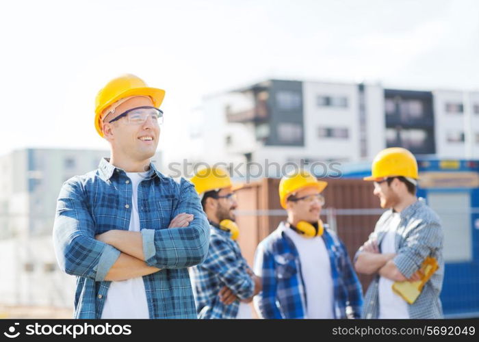 business, building, teamwork and people concept - group of smiling builders in hardhats outdoors