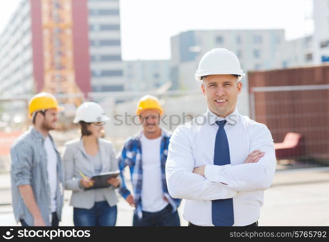 business, building, teamwork and people concept - group of smiling builders in hardhats outdoors