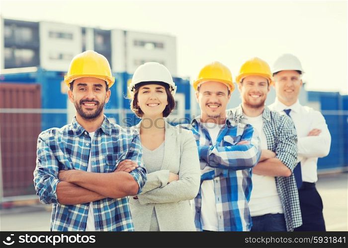 business, building, teamwork and people concept - group of smiling builders in hardhats outdoors