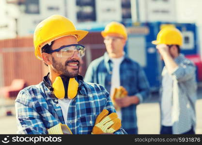 business, building, teamwork and people concept - group of smiling builders in hardhats outdoors