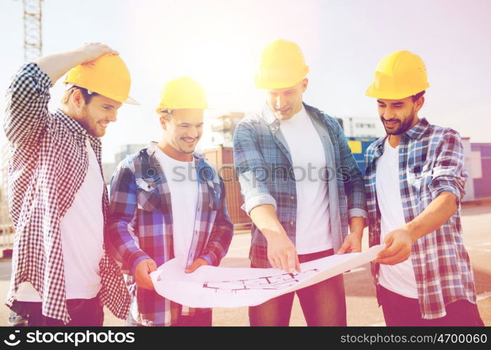 business, building, teamwork and people concept - group of smiling builders in hardhats with blueprint outdoors