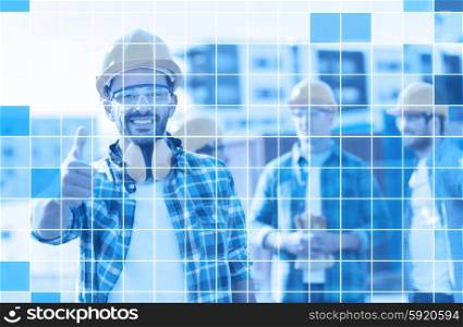 business, building, teamwork, gesture and people concept - group of smiling builders in hardhats showing thumbs up outdoors over blue squared grid background