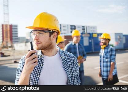 business, building, teamwork, technology and people concept - group of builders in hardhats with radio outdoors