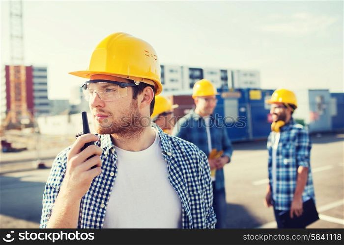 business, building, teamwork, technology and people concept - group of builders in hardhats with radio outdoors