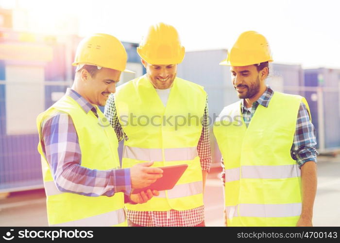 business, building, teamwork, technology and people concept - group of smiling builders in hardhats with tablet pc computer outdoors