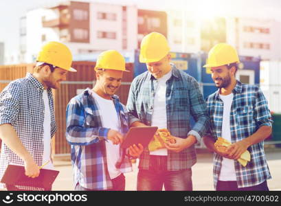 business, building, teamwork, technology and people concept - group of smiling builders in hardhats with tablet pc computer and clipboard outdoors