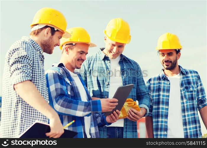 business, building, teamwork, technology and people concept - group of smiling builders in hardhats with tablet pc computer and clipboard outdoors