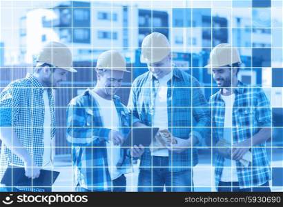 business, building, teamwork, technology and people concept - group of smiling builders in hardhats with tablet pc computer and clipboard outdoors over blue squared grid background