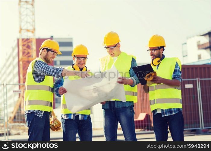 business, building, teamwork, technology and people concept - group of smiling builders in hardhats with tablet pc computer and blueprint outdoors