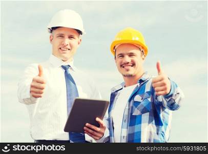 business, building, teamwork, technology and people concept - smiling builders in hardhats with tablet pc computer outdoors