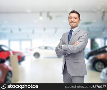 business, car sale, consumerism and people concept - happy man over auto show or salon background