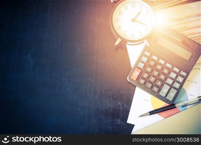 Business chart analysis report with pen, calculator and alarm clock on office table. Business background concept. Soft light and vintage filtered.