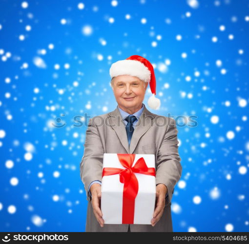 business, christmas, xmas, happiness concept - smiling old man in suit and santa helper hat with gift