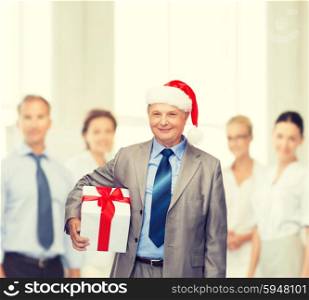 business, christmas, xmas, happiness concept - smiling old man in suit and santa helper hat with gift and team on the back