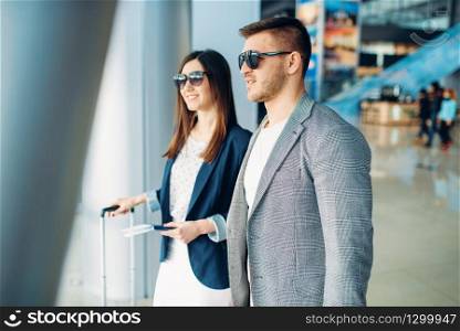 Business class passengers with baggage in airport, back view. Businessman and businesswoman in air terminal, negotiation trip. Business class passengers with baggage in airport