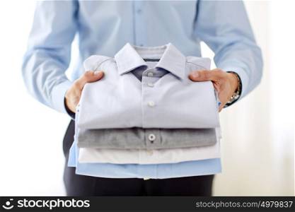 business, clothes, formal wear and people concept - close up of businessman holding shirts. close up of businessman holding shirts