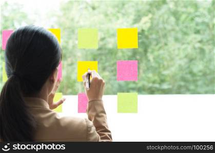 business colleague using notes on glass wall