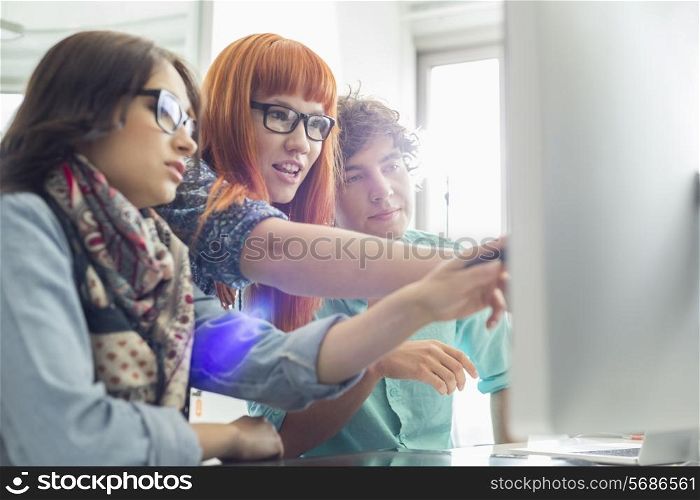 Business colleagues discussing over computer in creative office