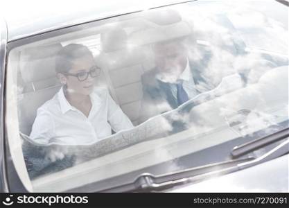Business colleagues discussing over map in car seen through windshield