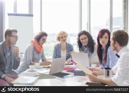 Business colleagues discussing over photographs at conference table in creative office