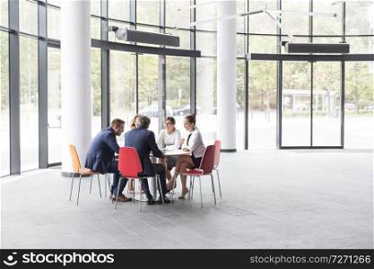 Business colleagues discussing while sitting at table during meeting in office lobby