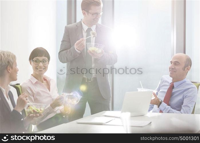 Business colleagues eating lunch in boardroom during meeting at office