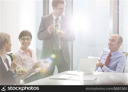 Business colleagues eating lunch in boardroom during meeting at office