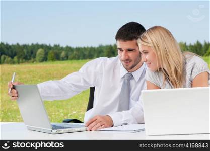 Business colleagues in sunny nature office working on laptop