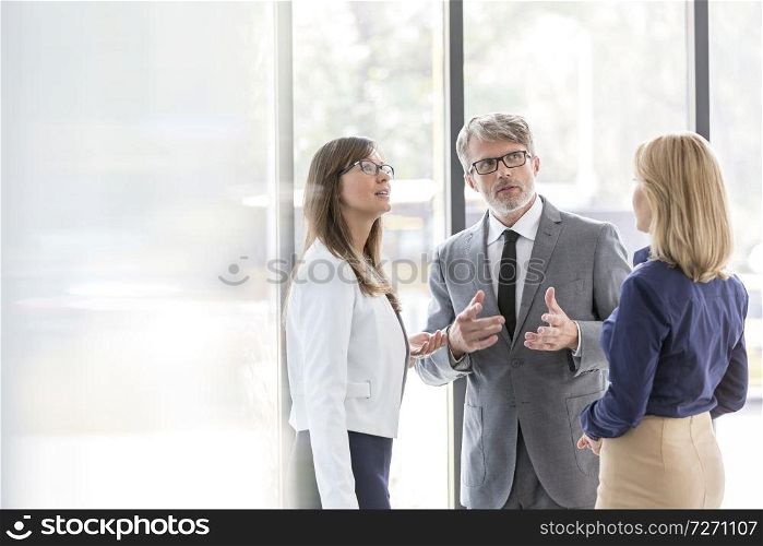 Business colleagues planning strategy during meeting against window at office