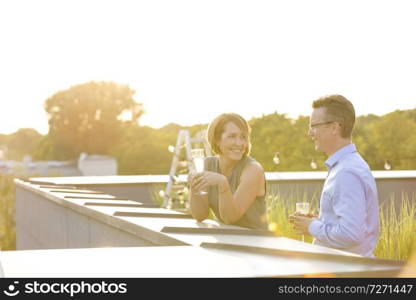 Business colleagues sitting while talking during party on rooftop