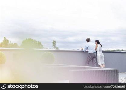 Business colleagues talking while standing at retaining wall in office