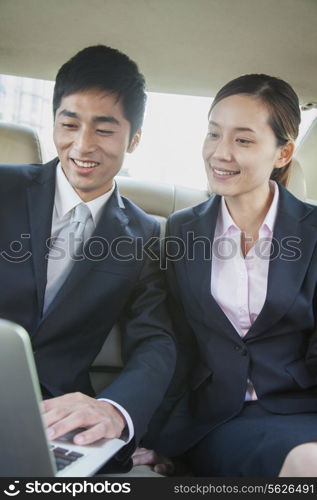 Business Colleagues Using Laptop in Back Seat Of Car