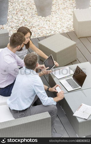 Business colleagues using technology sitting at office terrace