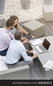 Business colleagues using technology sitting at office terrace