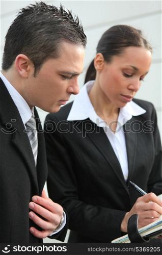 Business colleagues writing in a personal organizer