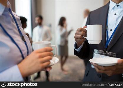 business, communication and education concept - international group of people with conference badges drinking coffee and talking at brake. business people with conference badges and coffee